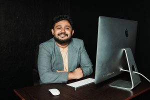 Confident businessman sitting at desk, working on computer in modern office