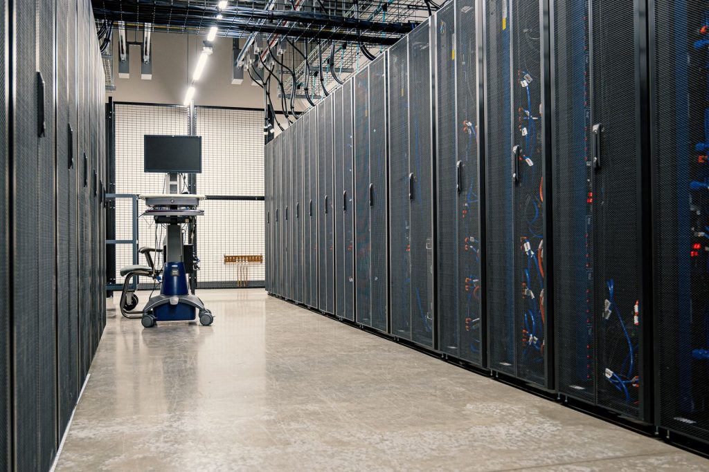 Rows of steel server racks with networking equipment and cables in a contemporary data center
