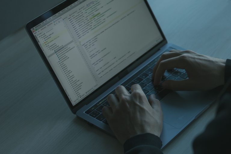 A person typing code on a laptop with a focus on cybersecurity and software development