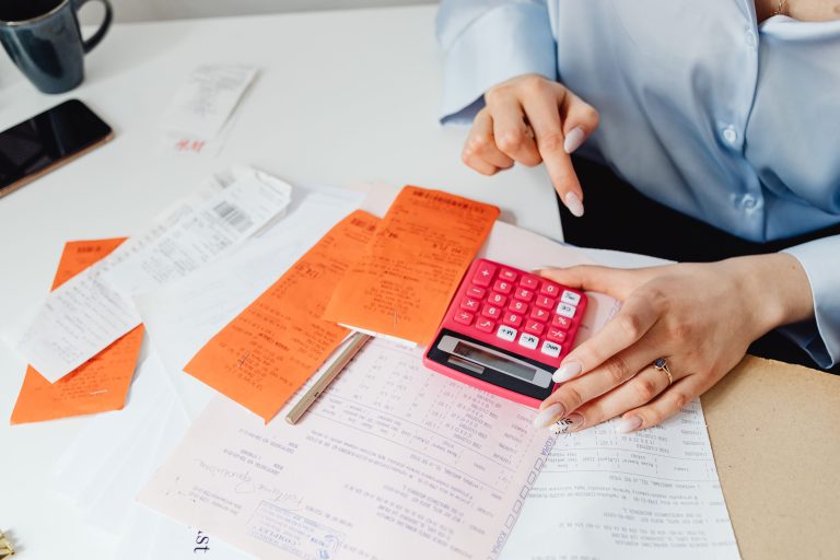 Person reviewing receipts with a calculator