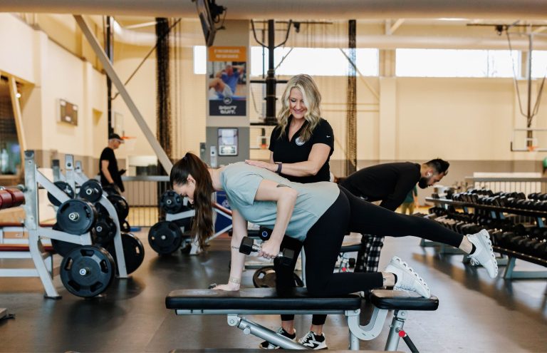 Trainer guides a client through a strength exercise