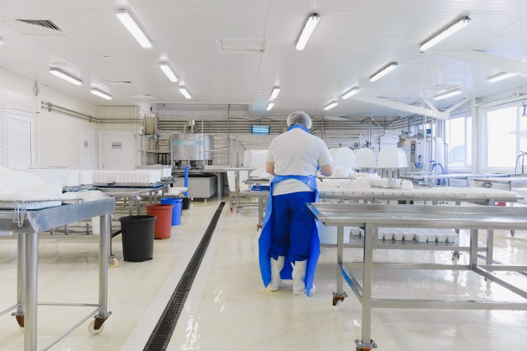 Worker in a clean production room with stainless equipment