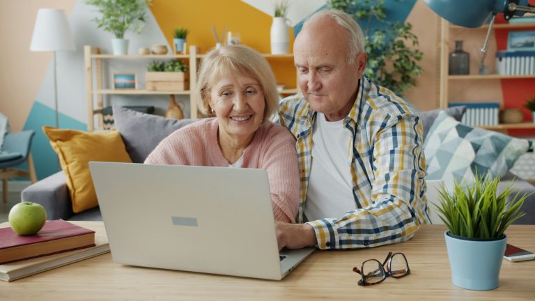 Older couple reviews retirement planning information on a laptop