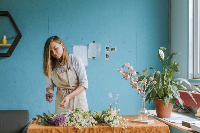 A florist arranges flowers on a table in a studio
