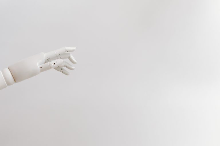 Illustrative photo of a white robotic hand against a plain background